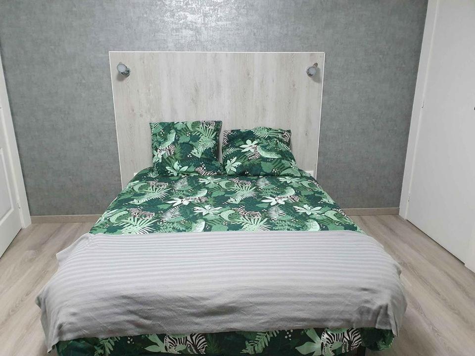 a bed with green and white sheets and pillows at Chambres la Fabière Vauciennes -Epernay in Vauciennes