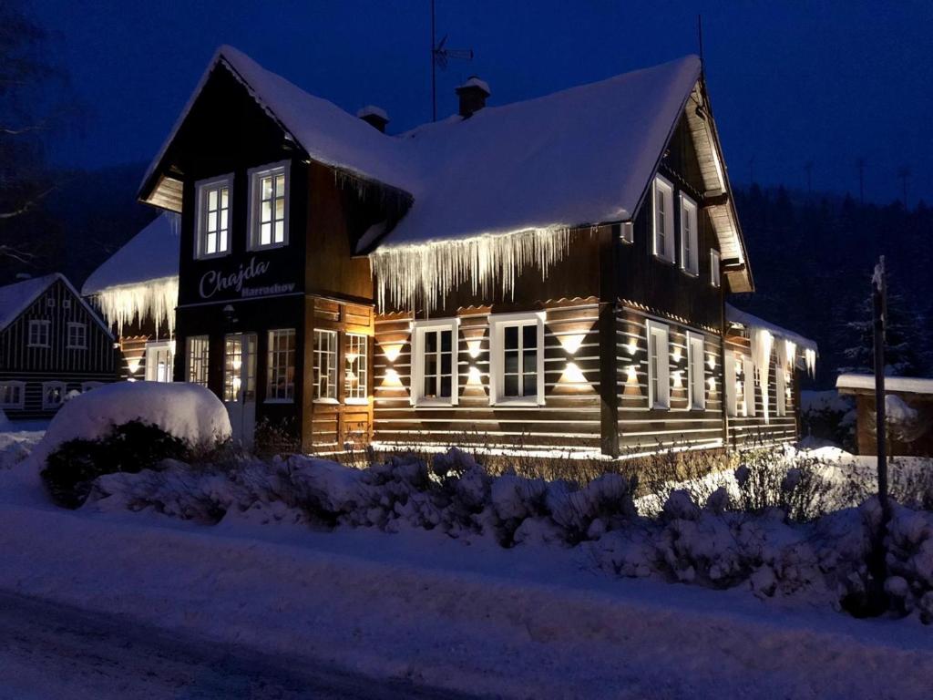 a house covered in lights in the snow at night at Chajda Harrachov in Harrachov