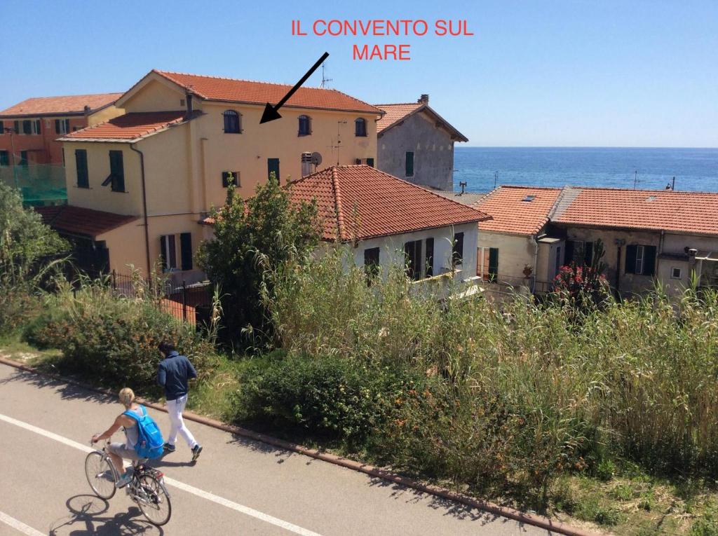 un homme faisant du vélo et un garçon faisant du skateboard sur une route dans l'établissement Il Convento sul Mare, à Santo Stefano al Mare