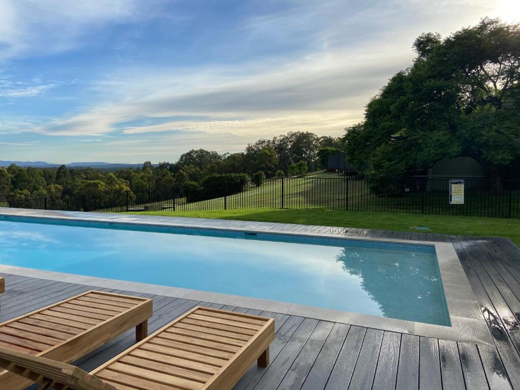 a swimming pool with two loungers on a wooden deck at Wine Country Villas in Pokolbin