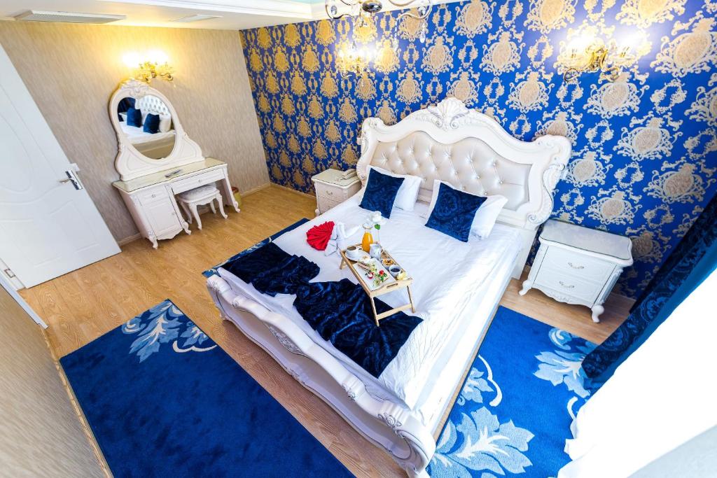 a bedroom with a large white bed with blue walls at Hotel Helin Central in Craiova