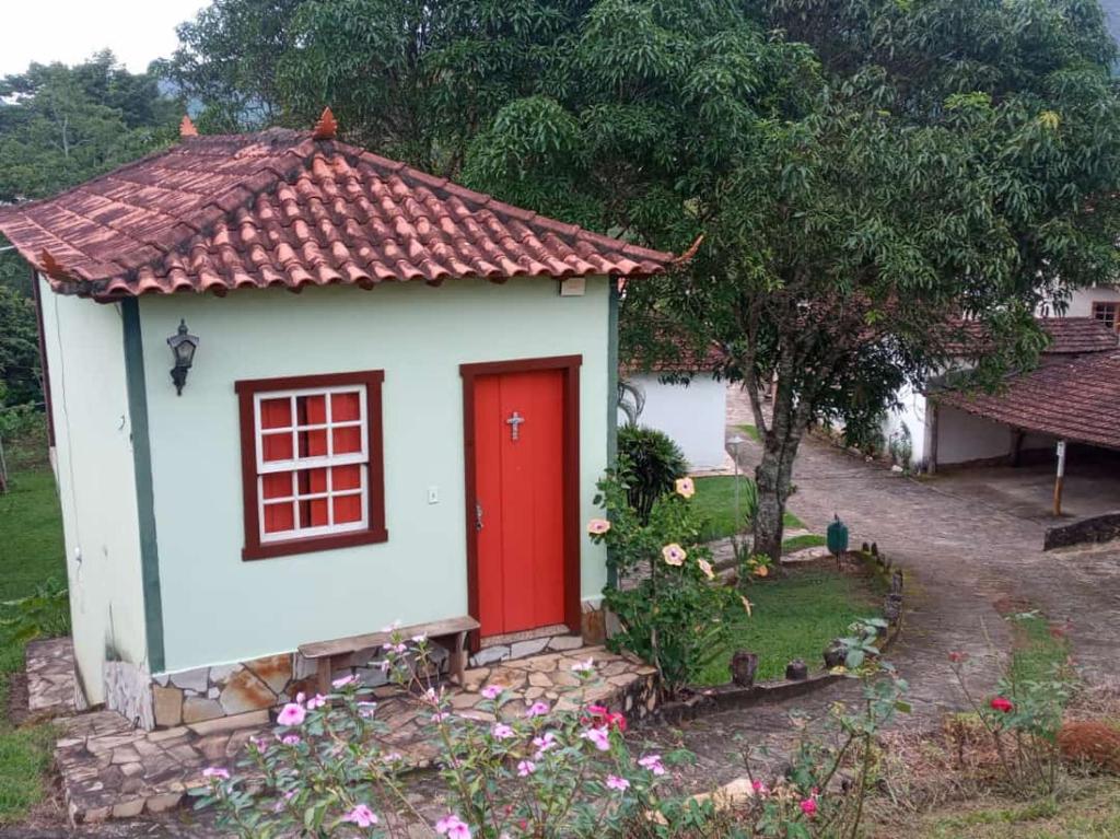 ein kleines Haus mit einer roten Tür im Hof in der Unterkunft Pouso Jequitibá in Tiradentes