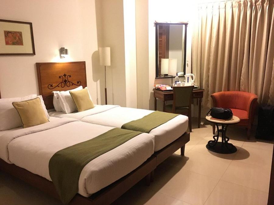 a hotel room with a large bed and a desk at NANI HOTELS & RESORTS in Kollam