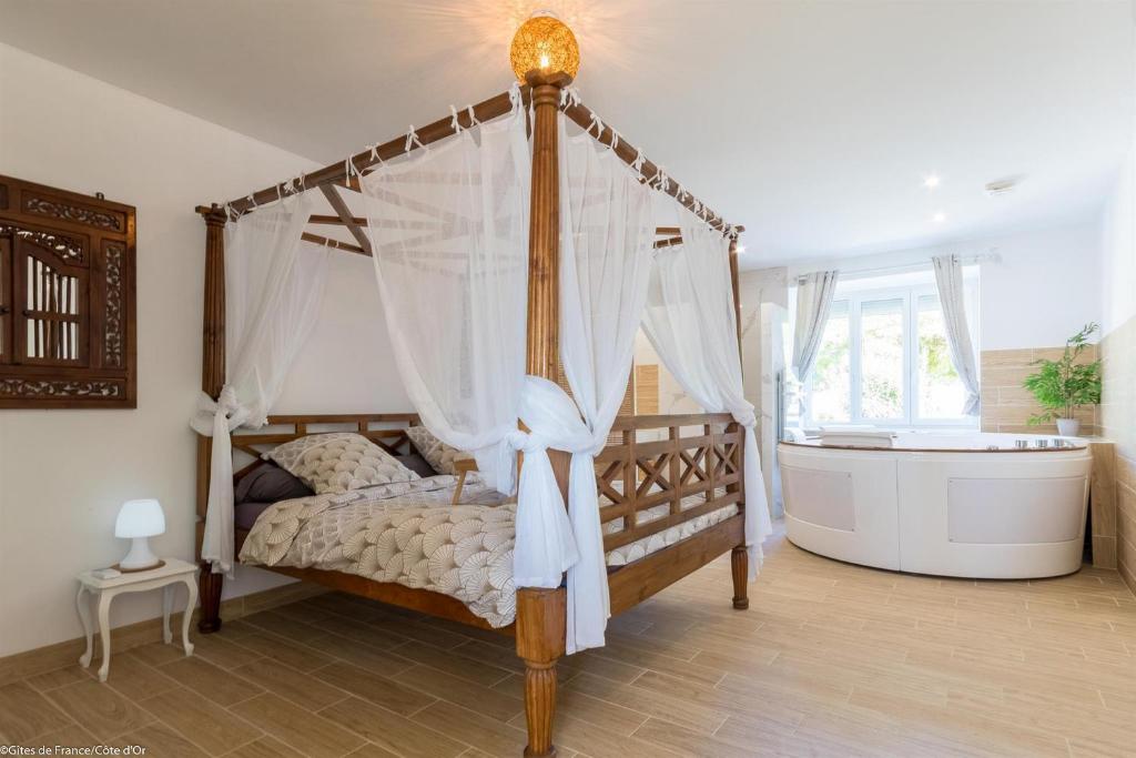 a bedroom with a canopy bed and a bath tub at Les Crus de Santenay in Santenay