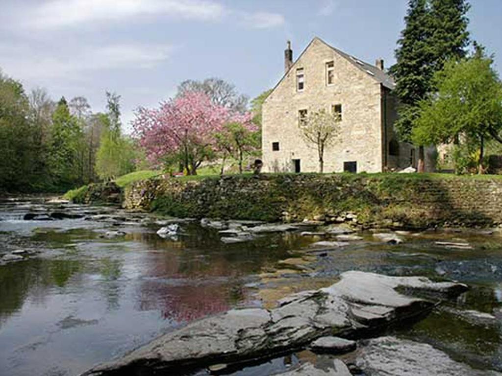 una casa de piedra a orillas de un río en Dilston Mill, en Hexham