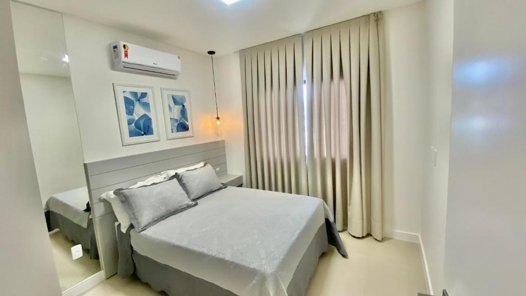 een witte slaapkamer met een bed en een raam bij HY Apart Hotel in Bombinhas