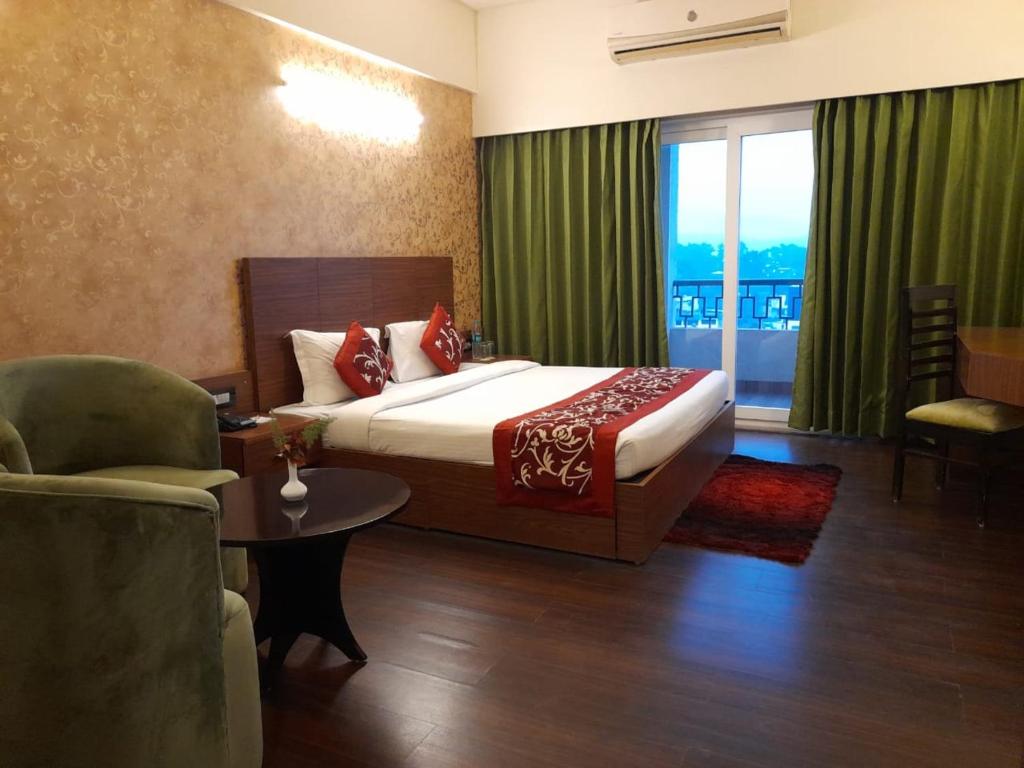 a hotel room with a bed and a chair and a window at Hotel Livbox in Dehradun