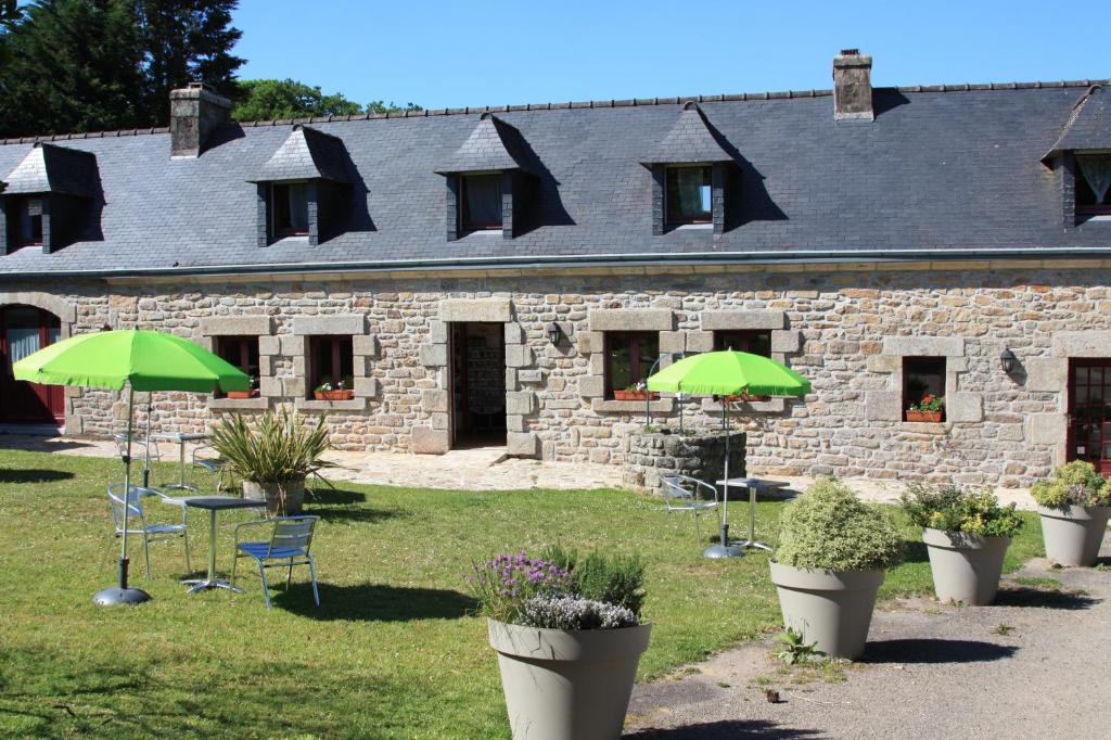 un bâtiment avec des chaises et des parasols en face de celui-ci dans l'établissement Domaine de Lesvaniel, à Landudec