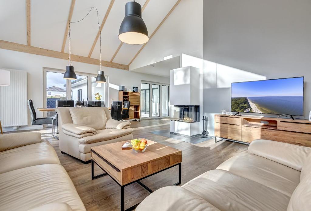 a living room with white furniture and a large screen tv at Haus Henny mit Sauna in Heringsdorf