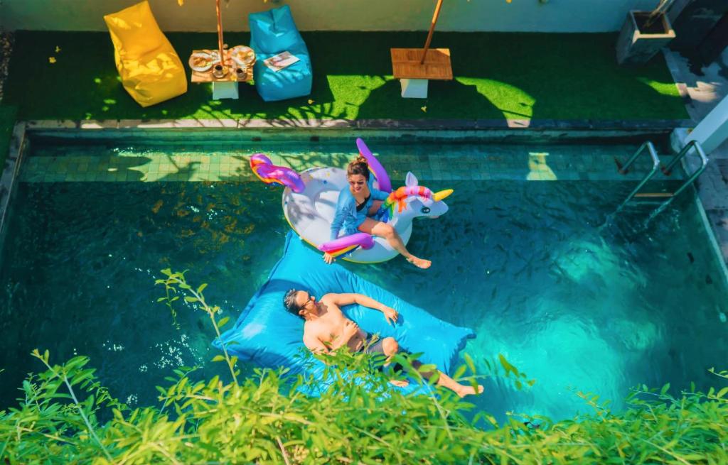 two people riding on a water slide in a pool at Bahana Guest House in Kuta