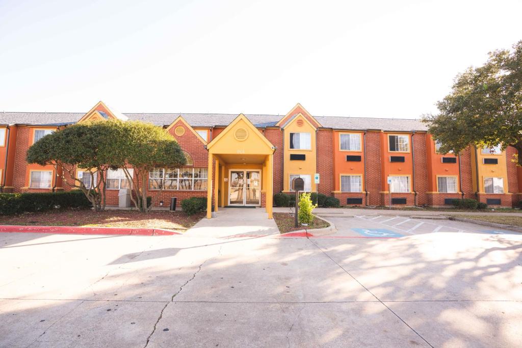 a large brick building with a yellow entrance at Regency Inn & Suites DFW in Euless