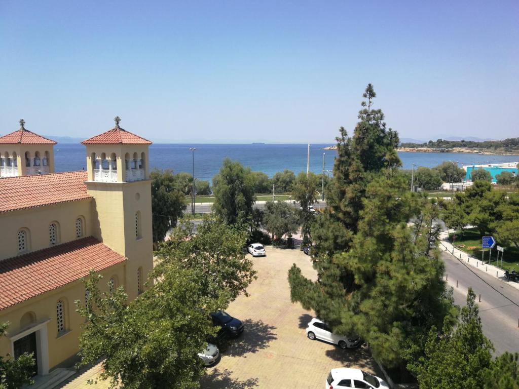 Blick auf ein Gebäude mit Bäumen und das Meer in der Unterkunft Miramare Hotel in Athen