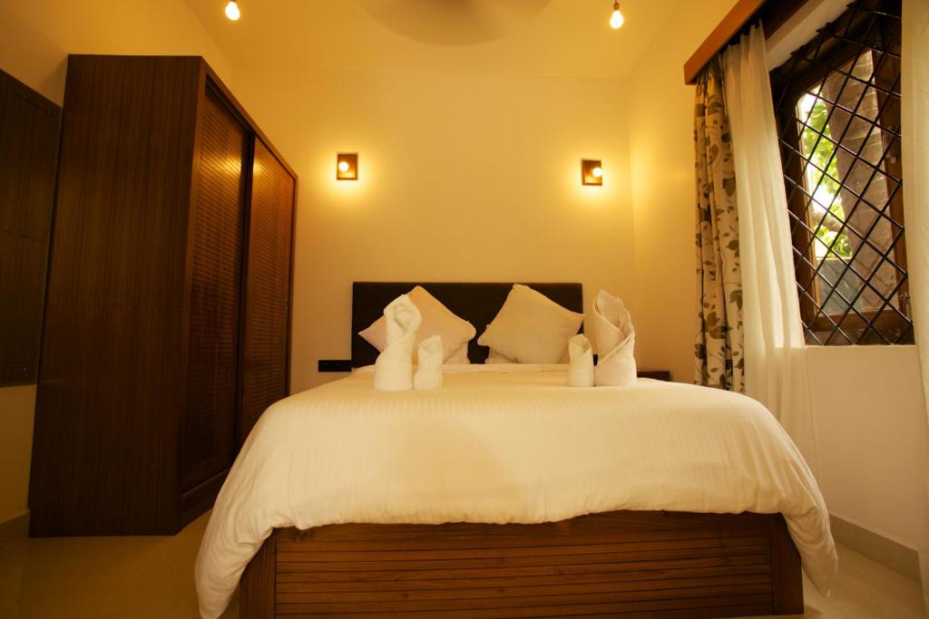 a bedroom with a bed with white sheets and a window at Dunhill Beach Resort in Agonda