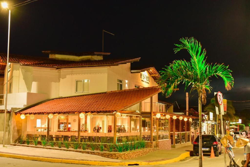un bâtiment situé dans une rue avec des palmiers la nuit dans l'établissement Le Soleil Pousada e Restaurante, à Praia do Frances