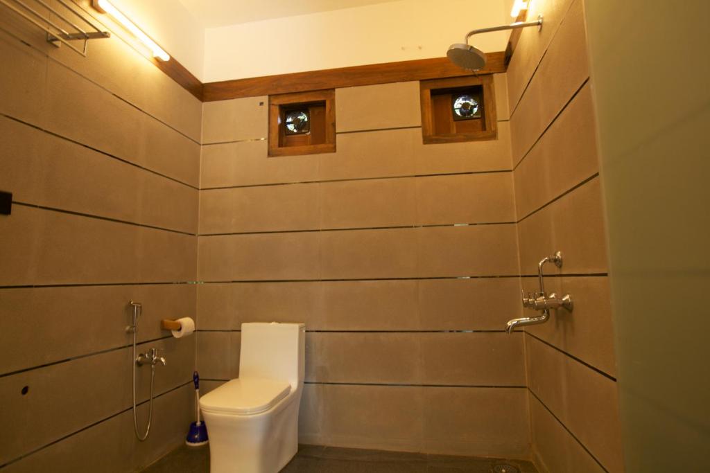 a bathroom with a toilet and two windows on the wall at Dunhill Beach Resort in Agonda
