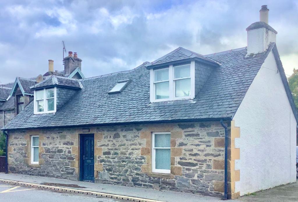 an old stone house with a black roof at Comfy 3-Bed Cottage in Newtonmore in Newtonmore