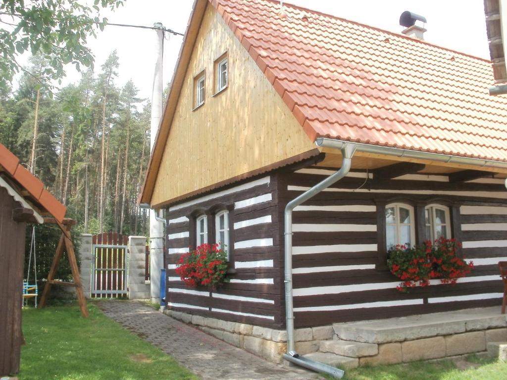 una casa con techo rojo y 2 ventanas y flores en Chalupa Erika, en Dobšín