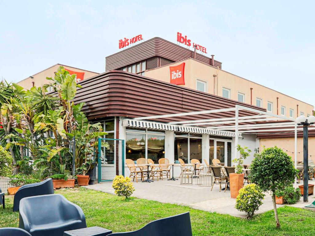 um restaurante com cadeiras e mesas em frente a um edifício em Ibis Valencia Alfafar em Alfafar