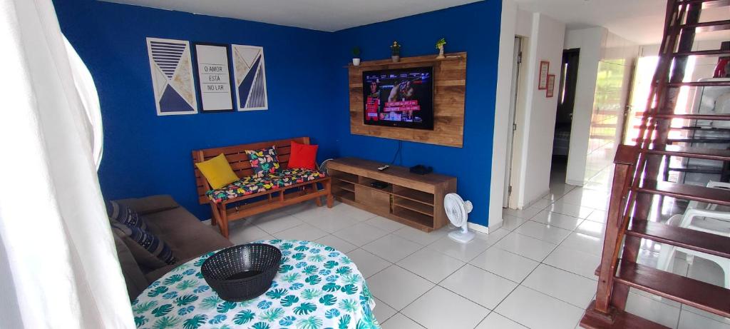 a living room with a blue wall and a tv at Promessa divina Carneiros in Tamandaré