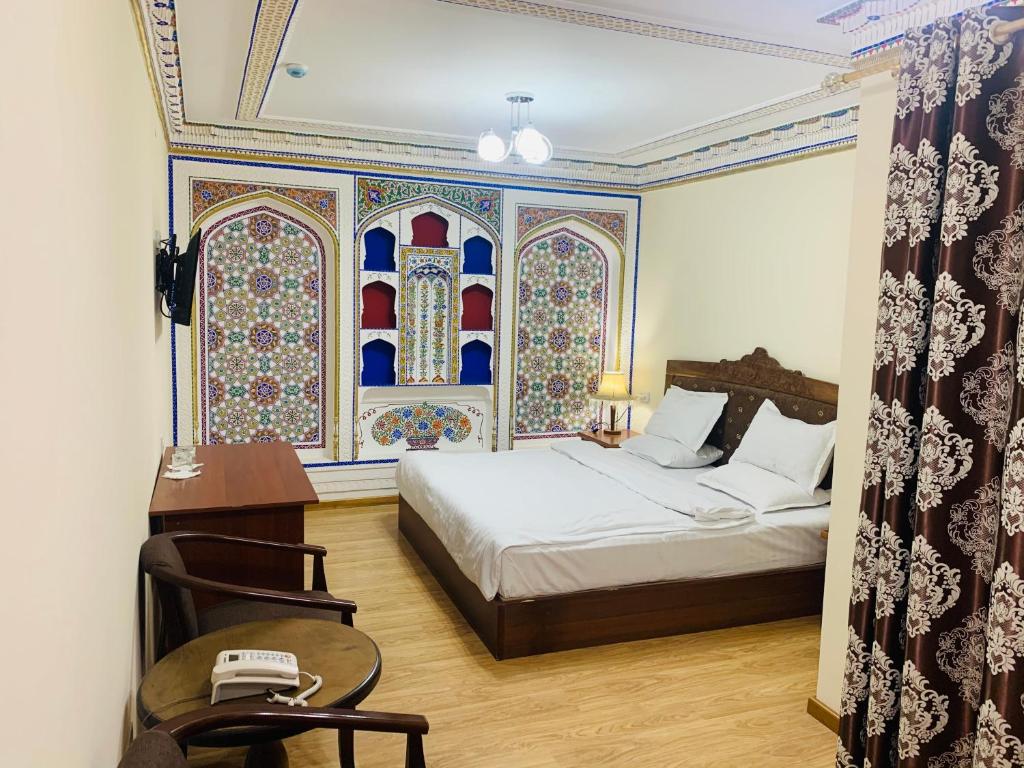 a bedroom with a bed and a desk with a phone at Hotel Fatima Boutique in Bukhara