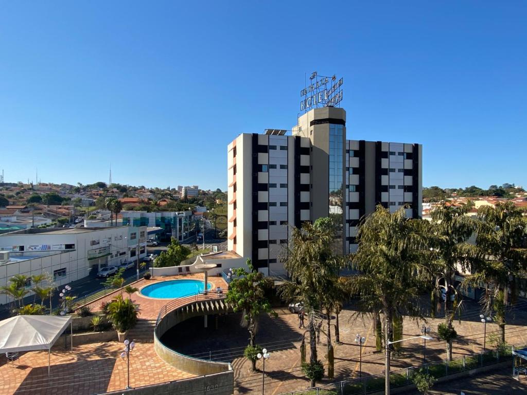 a view of a building with a pool and trees at HD Plaza Hotel in Assis