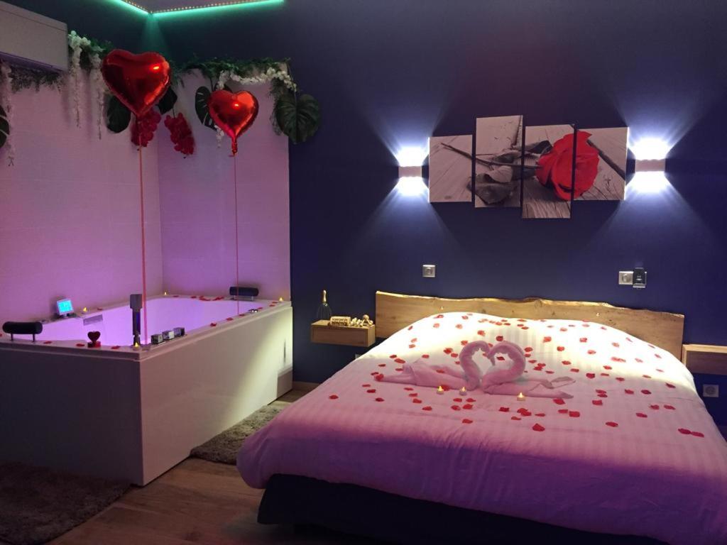L EDEN et sa love room avec balnéothérapie في ميزو-الفور: غرفة نوم مع سرير وحوض استحمام بقلوب عليه