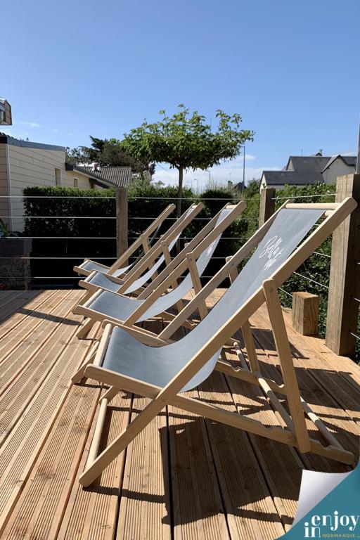 une rangée de chaises longues assises sur une terrasse dans l'établissement Villa Douce, à Agon-Coutainville