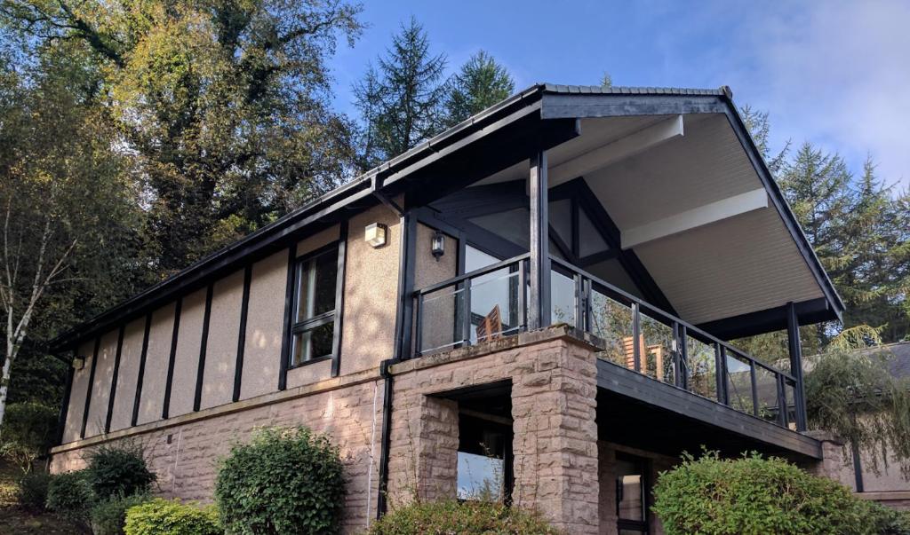 a house with black windows and a cat sitting on the balcony at Loch Lomond Lodge in Balloch