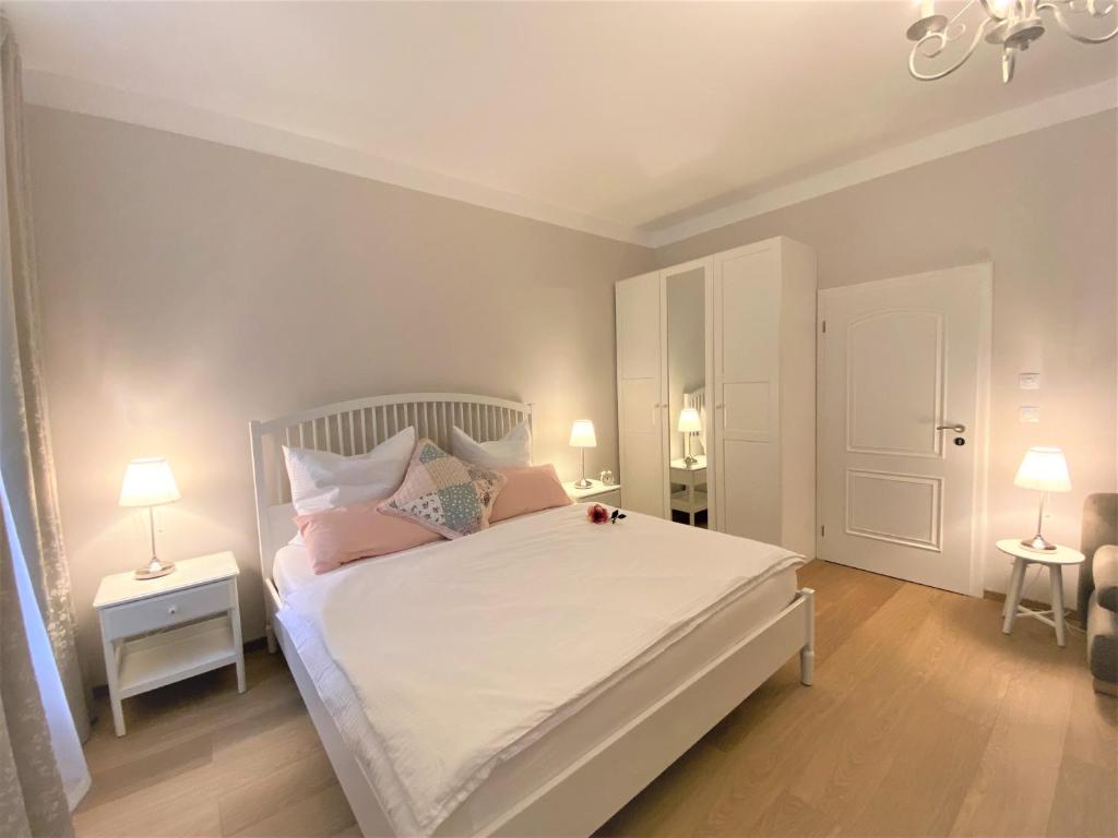 een slaapkamer met een groot wit bed met roze kussens bij Apartments Magnolia in Mariánské Lázně
