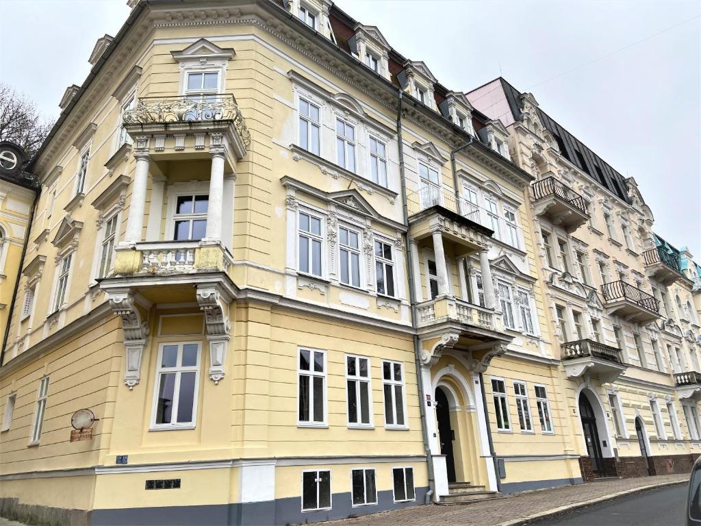 duży żółty budynek z oknami wychodzącymi na ulicę w obiekcie Apartments Magnolia w Mariańskich Łaźniach