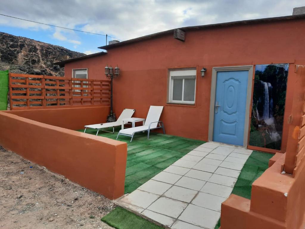 un patio con sillas blancas y una puerta azul en Casa rural, Naturaleza, Relax, Vacaciones en Teguitar