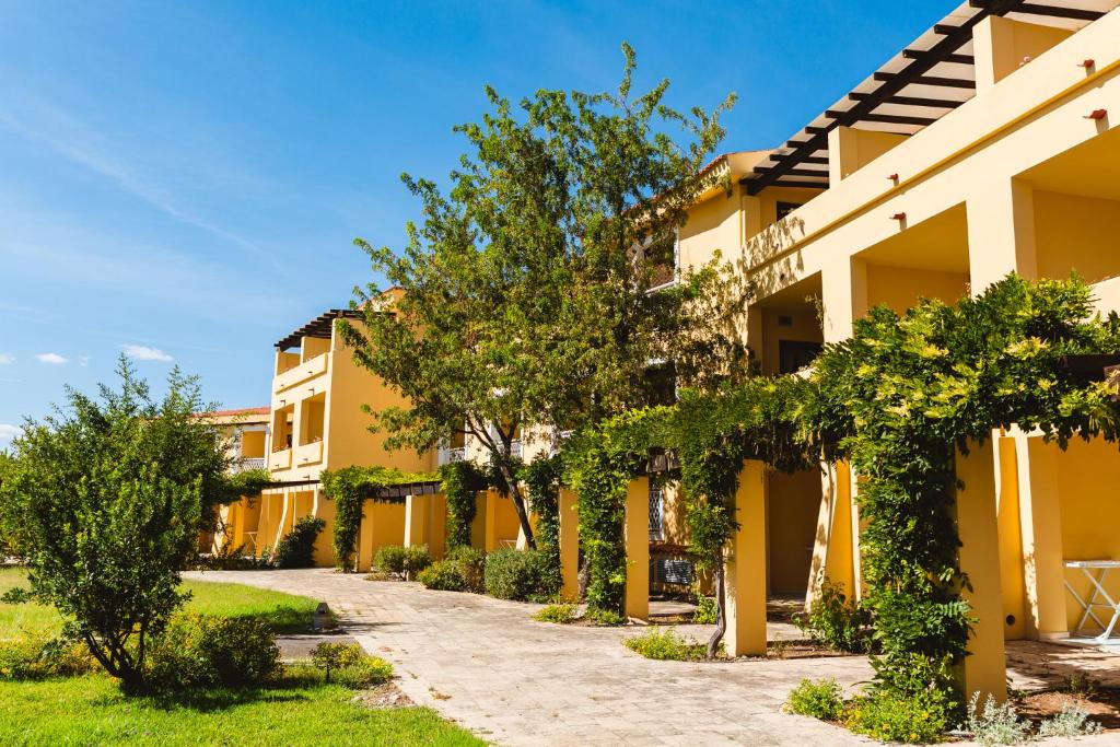 un bâtiment avec des arbres devant lui dans l'établissement Argonauti Greenblu Resort, à Marina di Pisticci