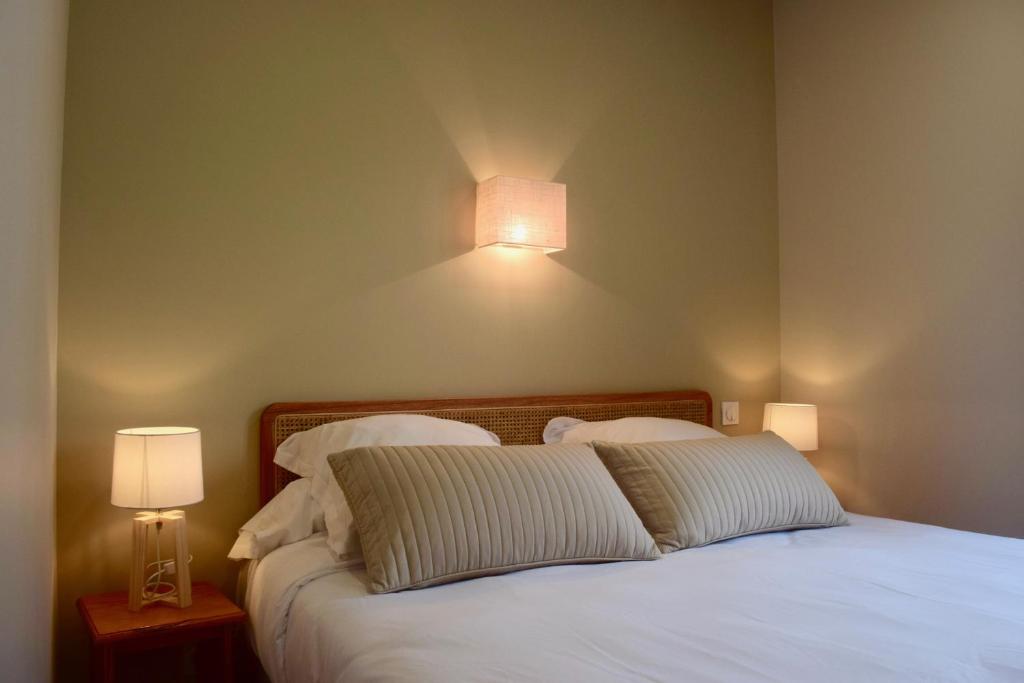 a bedroom with a bed with white sheets and two lamps at Hôtel et appartements les platanes in Thueyts