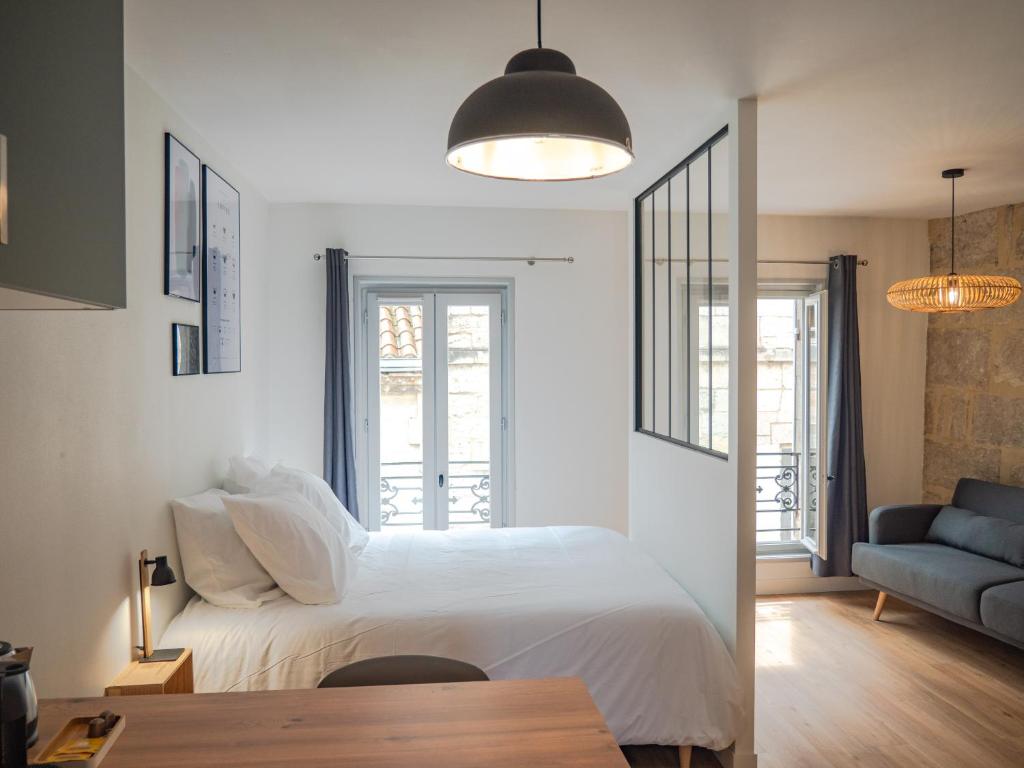 a bedroom with a white bed and a blue couch at Apparts Limogeanne - Clim - Centre historique in Périgueux