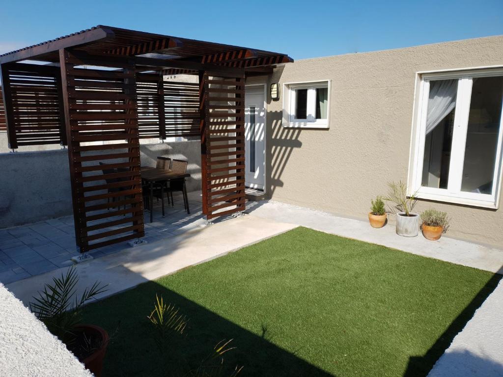 a patio with a wooden pergola and green grass at La Dolce Vita Apartments Unit 2 in Posedarje