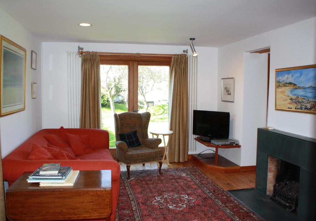 a living room with a red couch and a fireplace at Sylvan Orchard in Gullane