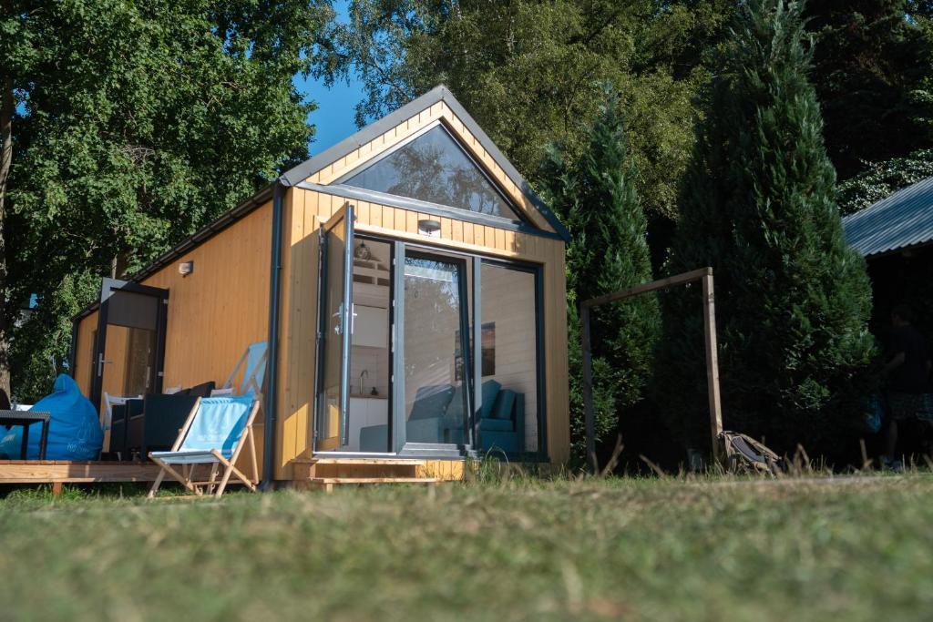 a tiny house in a field with two chairs at Pod Cyprysami - surf & family resort in Jastarnia
