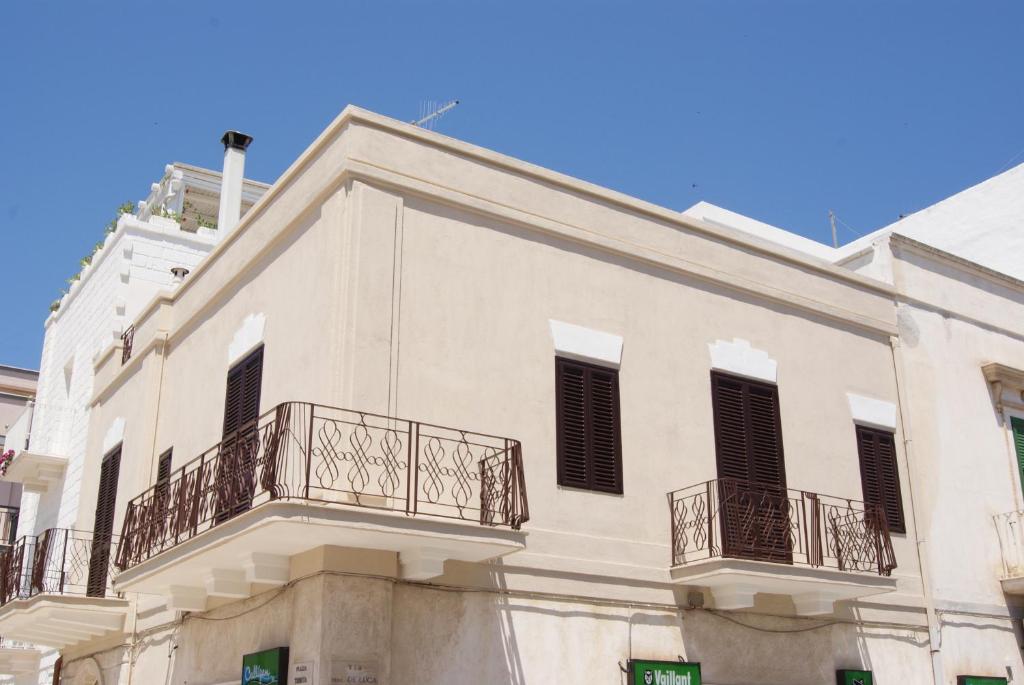 a white building with balconies on a street at Dimora Trinity in Polignano a Mare