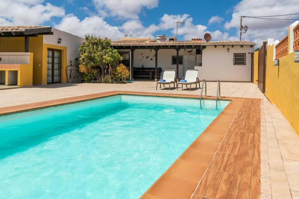 a swimming pool in front of a house at Casa rural con piscina privada Manitaga. in Tuineje
