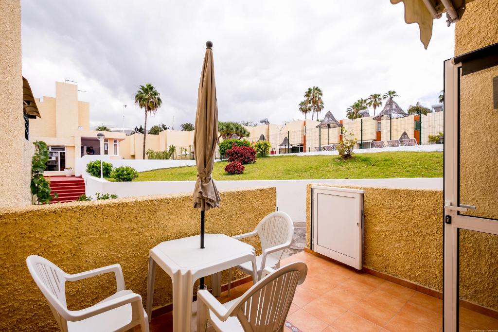 eine Terrasse mit Tisch und Stühlen und einem Sonnenschirm in der Unterkunft Bungalow Costa Adeje El Cortijo 2-9 in Playa de las Americas