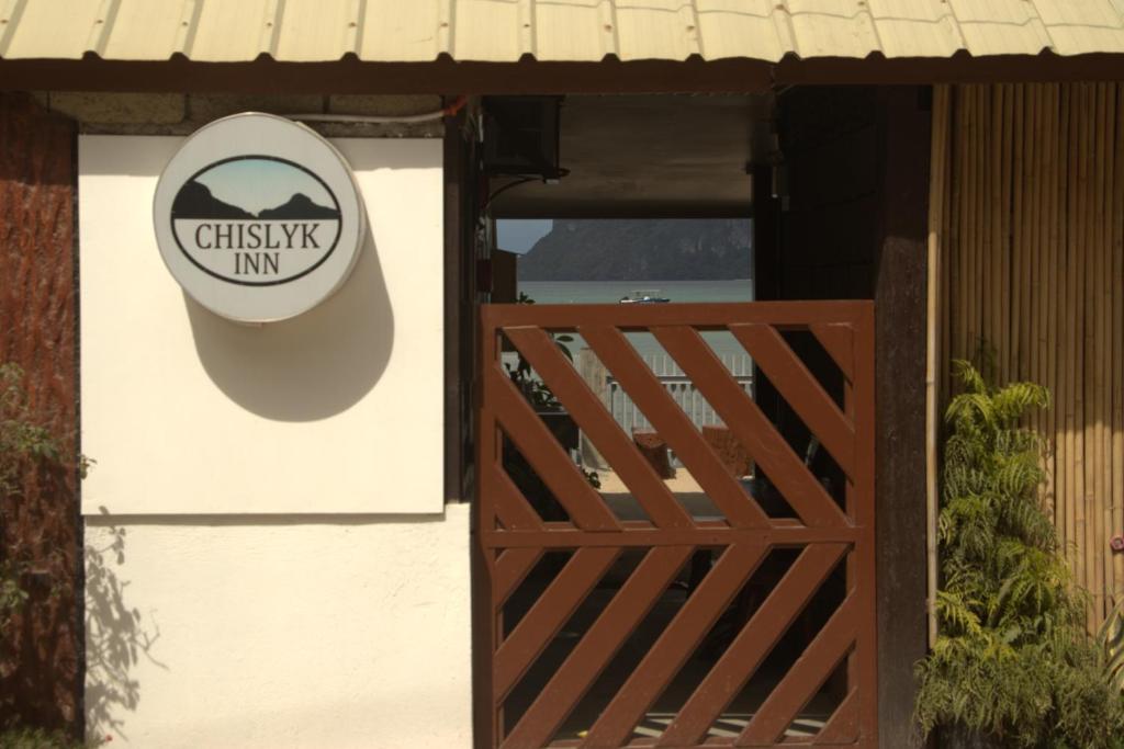 una señal en el lateral de una casa con una puerta de madera en Chislyk Inn en El Nido