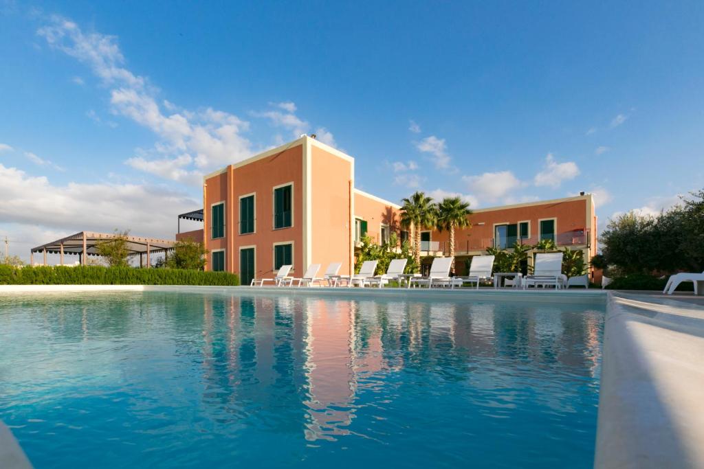 a swimming pool in front of a building with chairs at Corte Olea Resort in Paceco