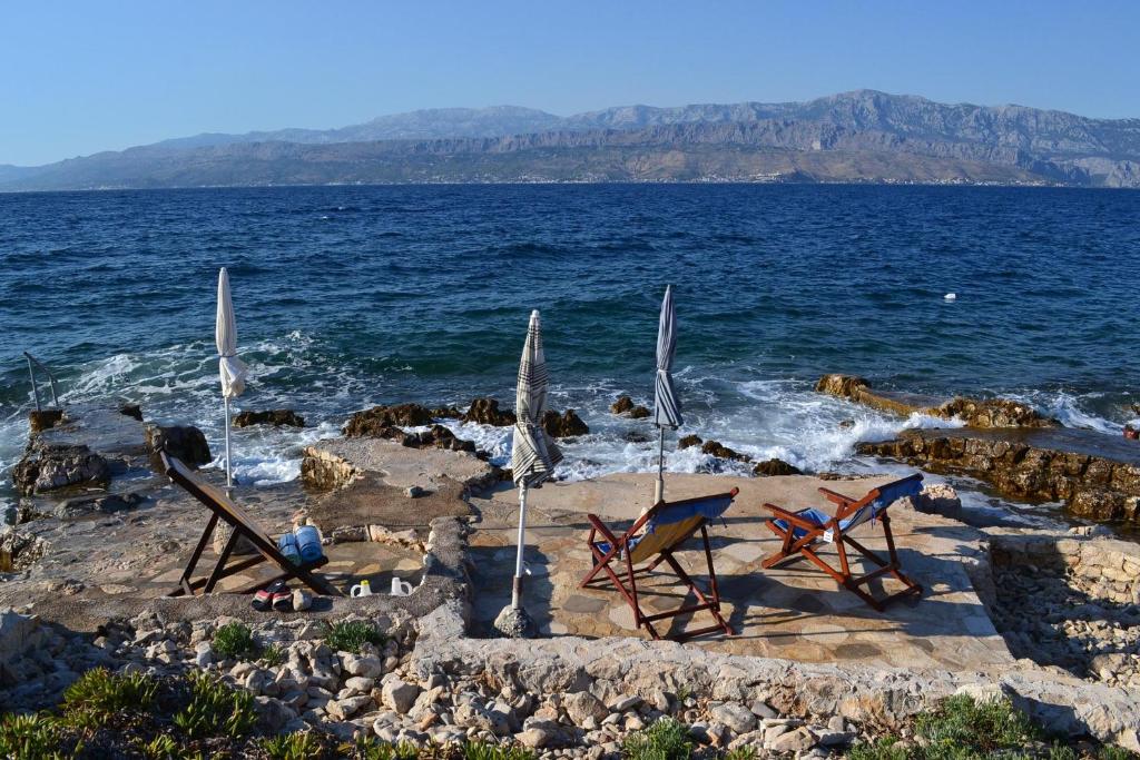 duas cadeiras e guarda-sóis numa praia com o oceano em Apartment Vila Punta 4234 em Splitska