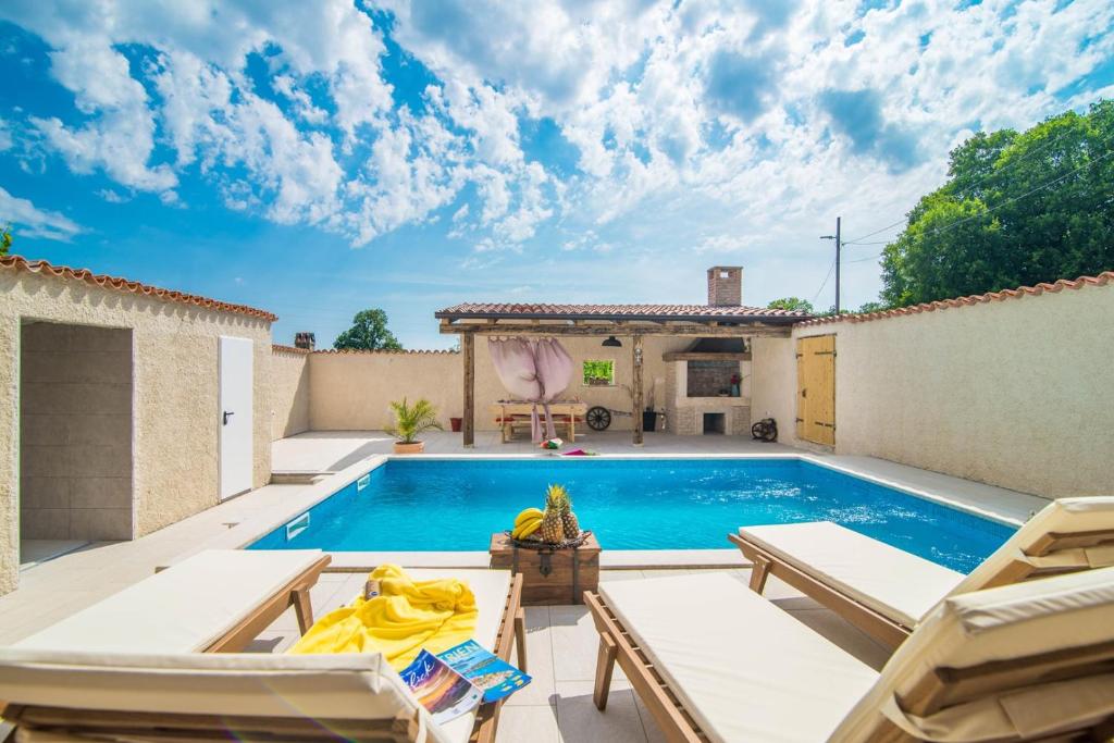 a pool in a backyard with chairs and a house at Holiday House Eleonora in Barban