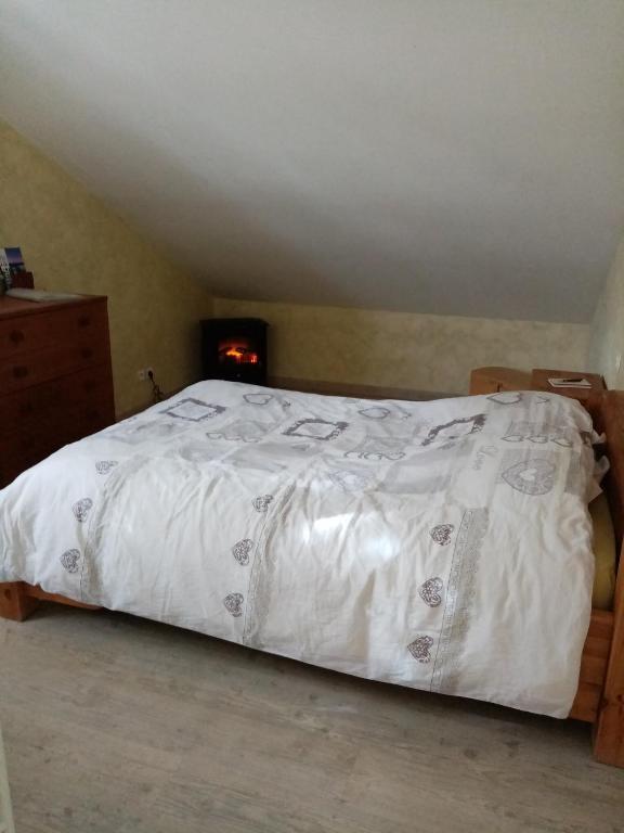a bed with a white comforter in a bedroom at Les lutins in Saffloz