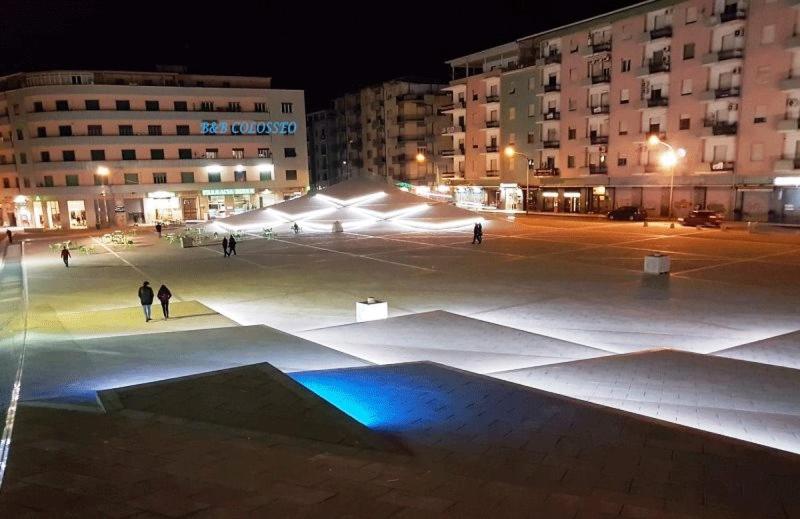 un ampio parcheggio con persone che camminano di notte di B&B COLOSSEO a Cosenza