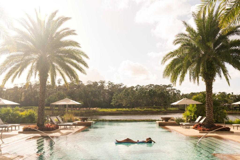 two people swimming in a pool with palm trees at Four Seasons Resort Orlando at Walt Disney World Resort in Orlando