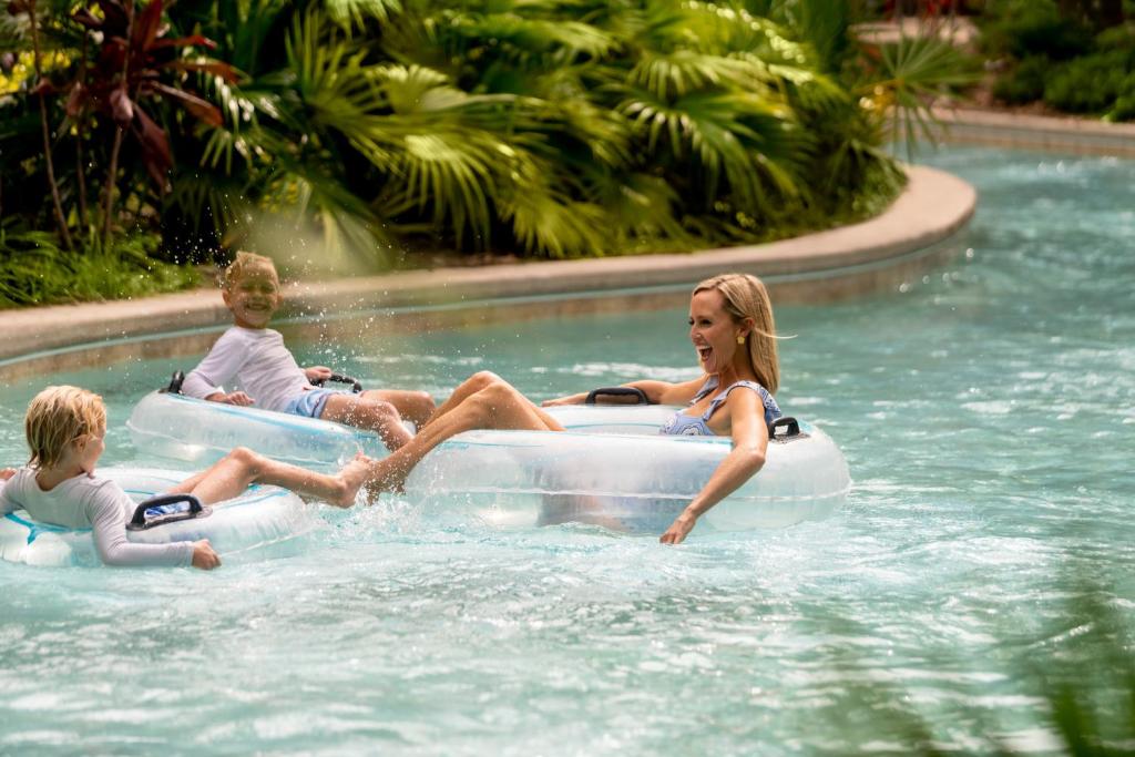 two children and a woman riding on an inner tube in a swimming pool at Four Seasons Resort Orlando at Walt Disney World Resort in Orlando