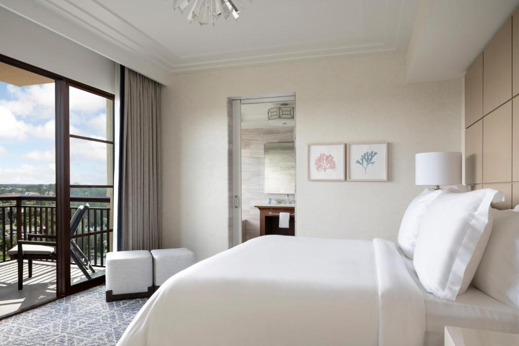 a white bedroom with a bed and a balcony at Four Seasons Resort Orlando at Walt Disney World Resort in Orlando
