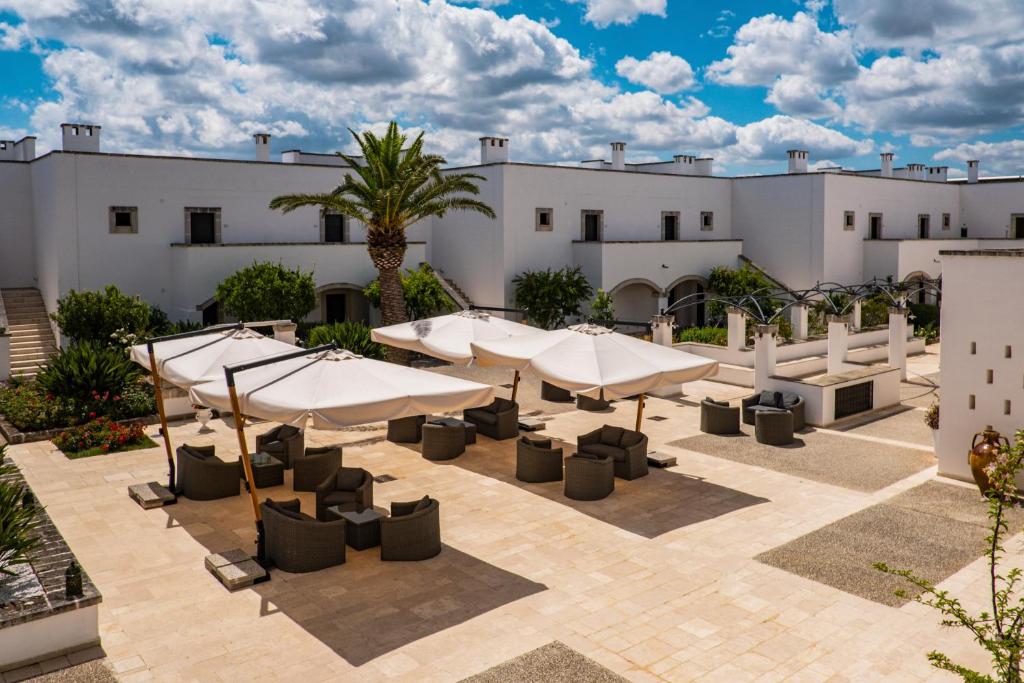 a patio with umbrellas and tables in front of a building at Borgobianco Resort & Spa Polignano - MGallery Collection in Polignano a Mare